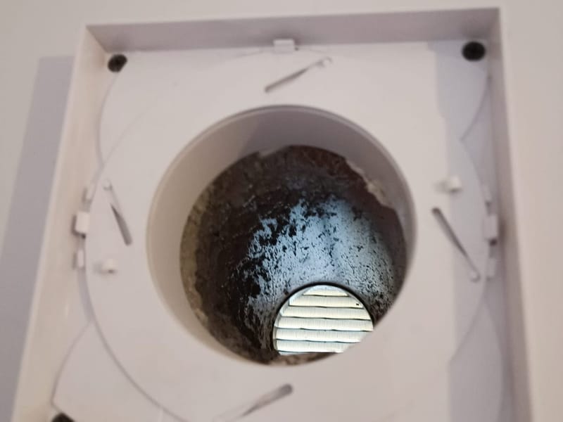 Extract fan cover opened to show the duct behind it