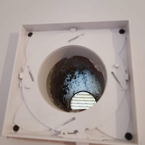 Extract fan cover opened to show the duct behind it